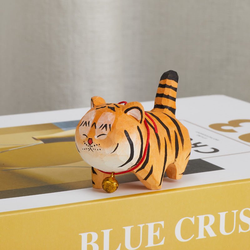 Handcrafted wooden tiger figurine with a red collar and bell side view