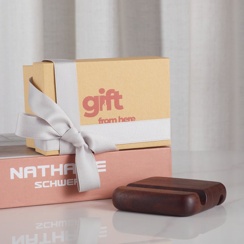 Gift box with ribbon next to wooden phone stand holder