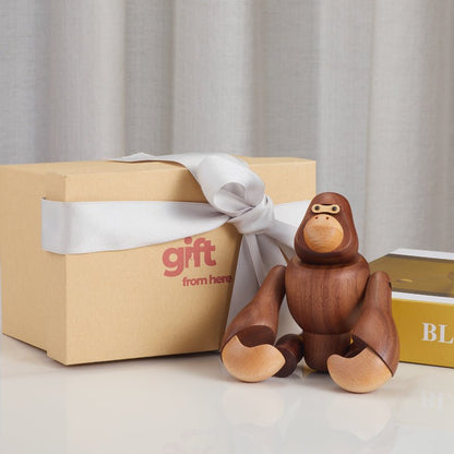 Gift box with a wooden gorilla figurine and a silver ribbon