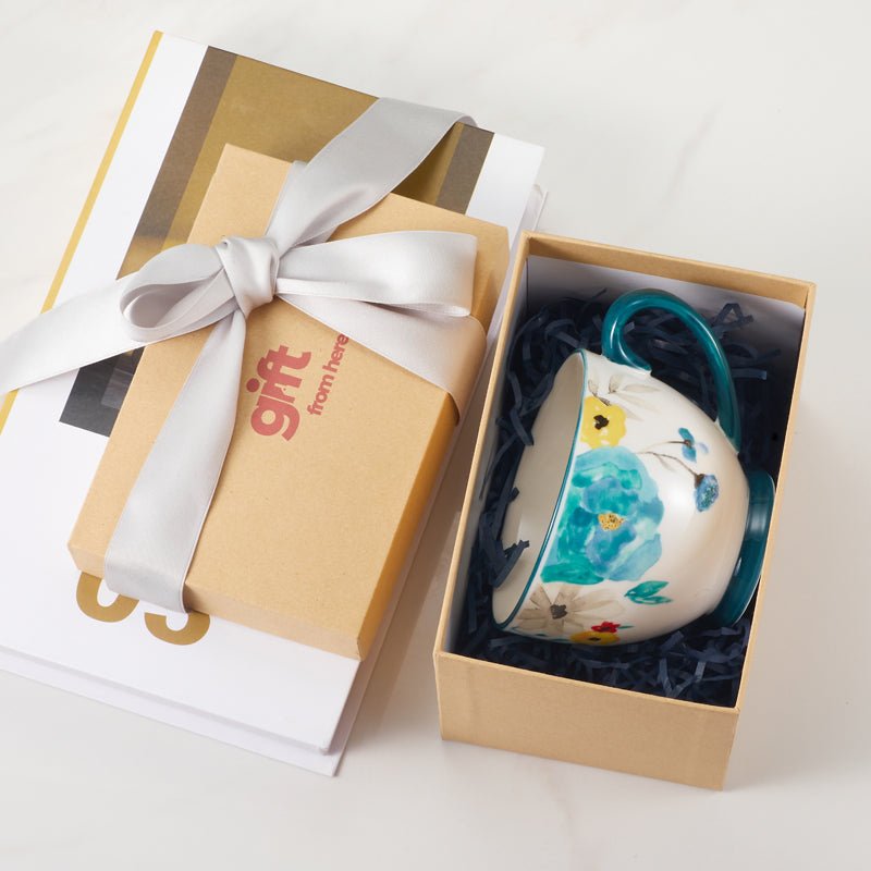 Floral-patterned ceramic mug with blue handle in a gift box.