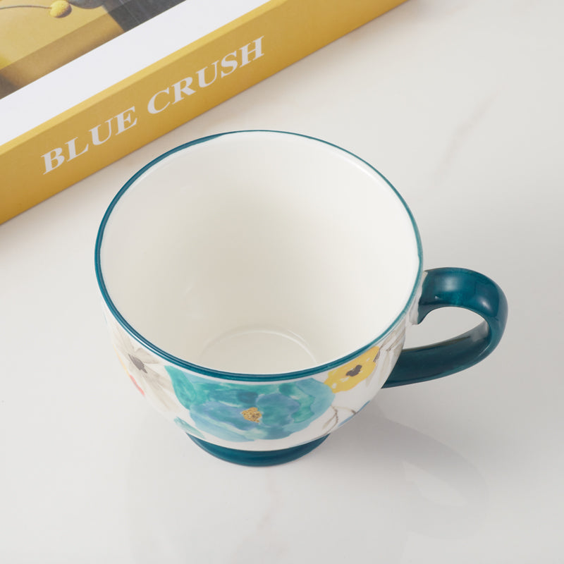Top view of floral-patterned ceramic mug with blue handle.